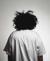 Young man with curly hair facing away against a plain backdrop photo