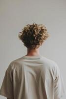 joven hombre con Rizado pelo frente a lejos en un minimalista ajuste foto