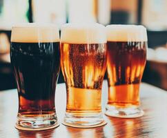 Beer mugs with foam on a wooden table in a busy bar photo