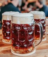 Beer mugs with foam on a rustic wooden table in a lively bar photo