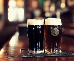 Two glasses of dark and light beer on a bar counter in a pub photo