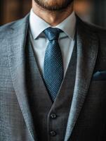 Man in a tailored gray suit with a blue tie, indoors photo