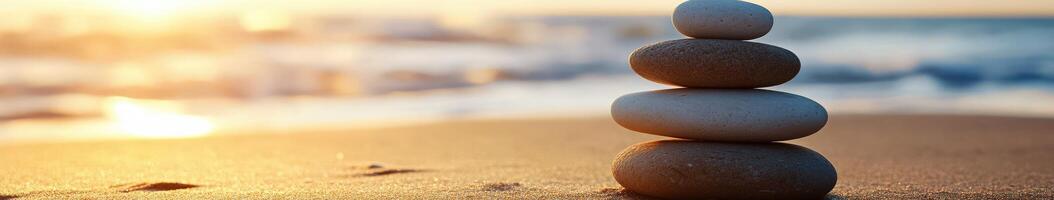 Stacked zen stones on a sandy beach at sunset photo