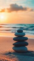 Stacked zen stones on a beach during sunset with ocean waves photo