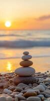 Stacked zen stones on a beach at sunset with gentle waves in the background photo