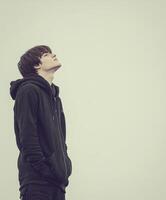 High school boy gazing up at the cloudy sky during late afternoon photo