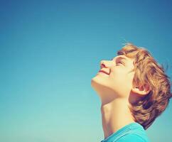 High school boy gazing up at the clear blue sky on a sunny day photo