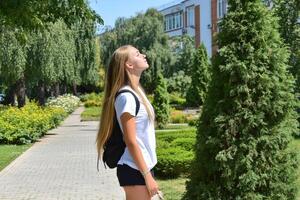High school girl gazing at the sky in a sunny park during summer photo