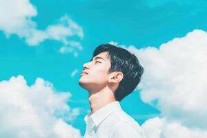 High school boy gazing at the bright sky with fluffy clouds on a sunny day photo