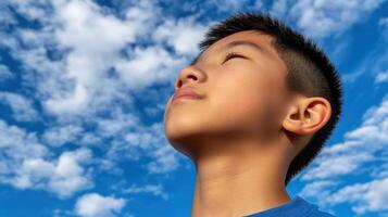 High school boy gazing up at a bright blue sky during the day photo