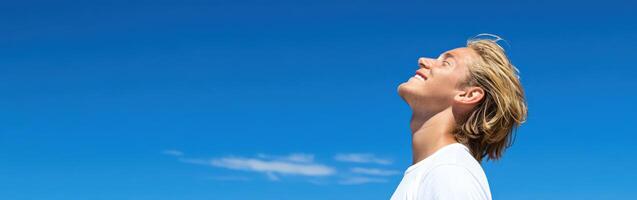 High school boy looking up at the clear blue sky during midday photo