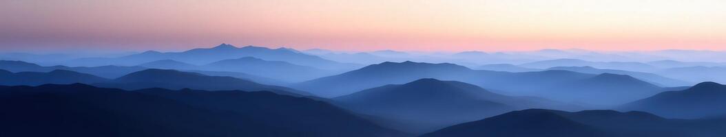Mountains shrouded in evening fog with soft pastel sky at dusk photo