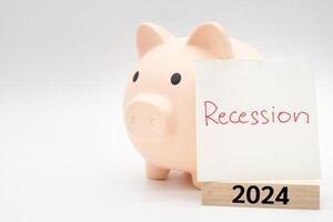 Hand writing Recession Warning on paper note with piggy bank. 2024 Wooden block. Global economic crisis. Recession business and stock crisis concept. photo