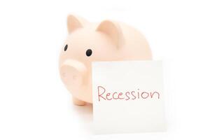 Hand writing Recession Warning on paper note with piggy bank. Global economic crisis. Recession business and stock crisis concept. photo