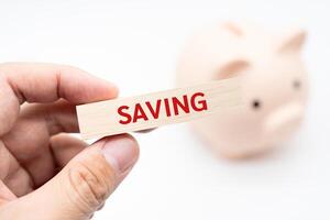 Text SAVING on wooden block with piggy bank on the background. Financial and business concept. retirement saving concept. Concept of money saving for rainy day. photo