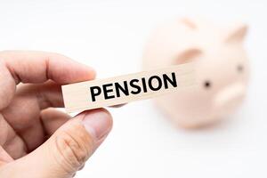 Text PENSION on wooden block with piggy bank on the background. Financial and business concept. retirement saving concept. photo