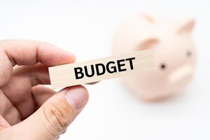 Text BUDGET on wooden block with piggy bank on the background. Financial and business concept. Budget planning concept. photo