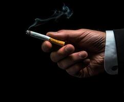 Close-up of a hand holding a cigarette with smoke on a black background photo