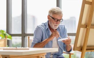 Senior man painting on canvas at home, Elderly man painting on a canvas, Happy retirement concepts photo