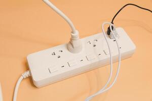 Electrical plug in outlet socket at home, Electrical plug in outlet socket at home, Energy efficiency concept, Power strip with extension cord on beige background, top view. photo