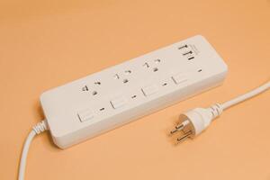 Electrical plug in outlet socket at home, Electrical plug in outlet socket at home, Energy efficiency concept, Power strip with extension cord on beige background, top view. photo