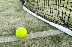 Tennis or paddle balls on synthetic grass of paddle court with net on the background photo