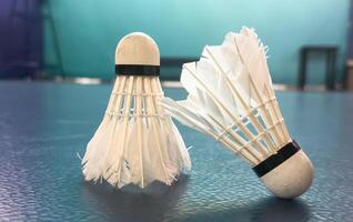 Cream white badminton shuttlecock and racket with neon light shading on floor in indoor badminton court, copy space, soft and selective focus. photo