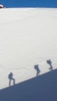 The person's shadow on a vertical cliff face. Silhouette of people climbing on overhanging cliff high above clouds and mountains, sun, beautiful colorful sky and clouds behind video