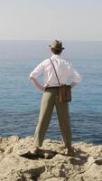 Man stands on the edge of the abyss and looks at the sea. Stock. Man traveler looking for adventure video