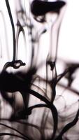 Light black smoke on white background. Abstract jets of black smoke on white isolated background. Soft dip of drops of black ink spreading in clear water video