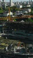 Top view of construction of large stadium in city. Stock footage. Process of building stadium on site with cranes in modern city. Construction of stadium with cranes on sunny day video