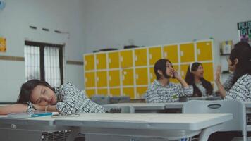 Student resting in classroom with peers talking in background video