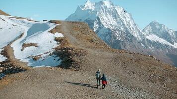 Hiking with child in mountains with snowy peaks. Creative. Mother and boy climb mountains on autumn sunny day. Family hiking in mountains with snowy peaks on sunny day video