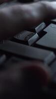 Close-up man presses keyboard key. Man presses button enter computer keyboard. Man's hand presses keyboard in light of computer screen video