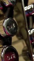 Metal stand with a chrome dumbbell. Stand with dumbbells in gym with hign contrast. Stand for dumbbells at the gym video