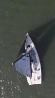 aéreo ver en solitario marinero en profundo azul agua. un solitario barco en el río. aéreo ver de verde islas y nubes a verano soleado Mañana video