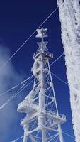 High voltage wires and poles are covered with frost on a blue cloudy winter sky. Clip. Low angle view of frozen power lines. video