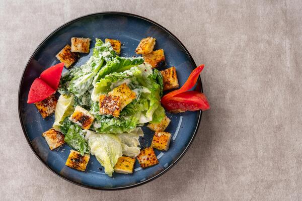 Caesar salad is a green salad of romaine lettuce and croutons dressed with mustard, Parmesan cheese, and garlic bread.