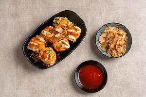 Takoyaki is a ball-shaped Japanese snack made of a wheat flour-based batter and cooked in a special molded pan photo