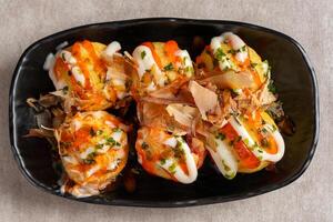 Takoyaki is a ball-shaped Japanese snack made of a wheat flour-based batter and cooked in a special molded pan photo