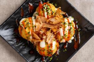 Takoyaki is a ball-shaped Japanese snack made of a wheat flour-based batter and cooked in a special molded pan photo