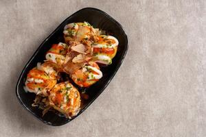 Takoyaki is a ball-shaped Japanese snack made of a wheat flour-based batter and cooked in a special molded pan photo