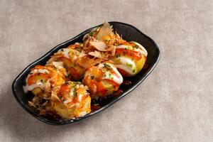 Takoyaki is a ball-shaped Japanese snack made of a wheat flour-based batter and cooked in a special molded pan photo