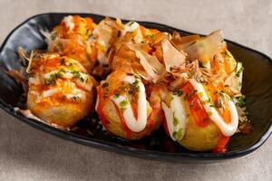 Takoyaki is a ball-shaped Japanese snack made of a wheat flour-based batter and cooked in a special molded pan photo