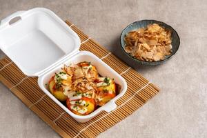 Takoyaki is a ball-shaped Japanese snack made of a wheat flour-based batter and cooked in a special molded pan photo
