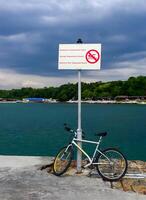 BULGARIA, VARNA - JUNE 06, 2013 - bike near the warning sign on the dam by the sea in Varna, Bulgaria photo