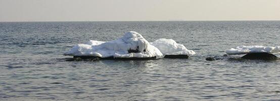 Iced rocks and stones near the shore in the Black Sea at the end of winter photo