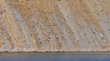 Vertically located layers of sedimentary rocks in coastal rocks in eastern Crimea photo