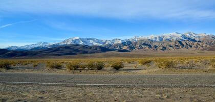 Landscape of wet clay desert in winter against the backdrop of snow-capped mountains in the Death Valley area photo