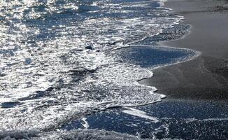 Bright reflections on the water on a sunny day on the sandy shore of the Black Sea photo